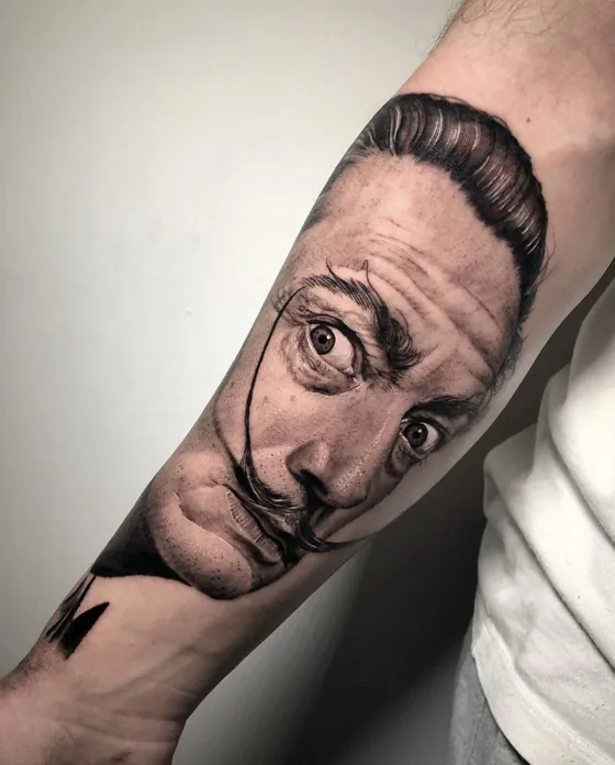 Porträt von Salvador Dalí mit gezwirbeltem Schnurrbart als Unterarmtattoo
