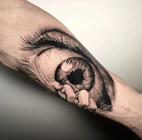 Fotorealistisches Auge mit Wimpern und Fingern als Unterarmtattoo