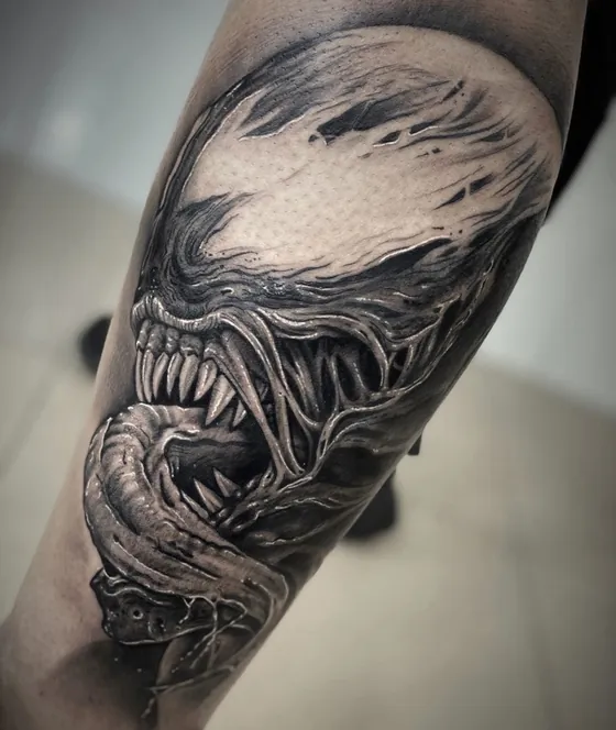 Venom-Motiv mit aufgerissenem Maul und Zähnen als Wadentattoo