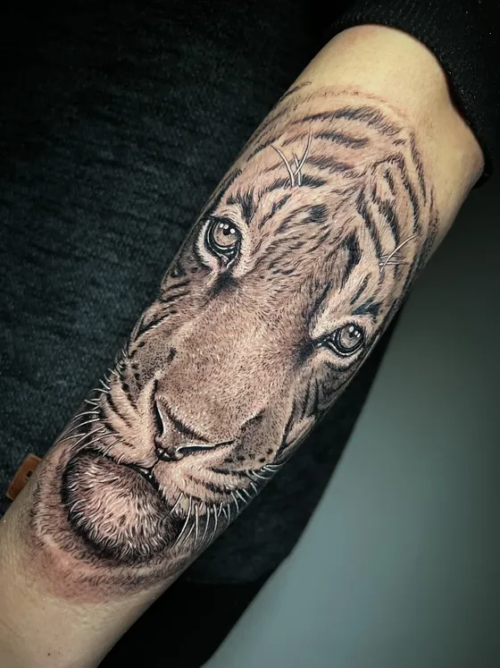 Realistischer Tigerkopf in Schwarz-Grau als Unterarmtattoo
