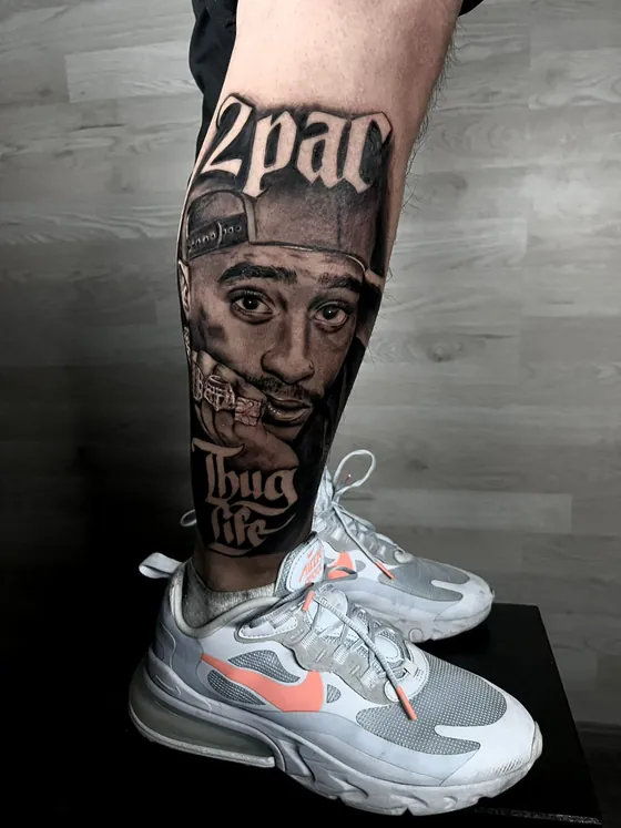 Porträt von Tupac Shakur mit Schriftzügen 2Pac und Thug Life als Wadentattoo