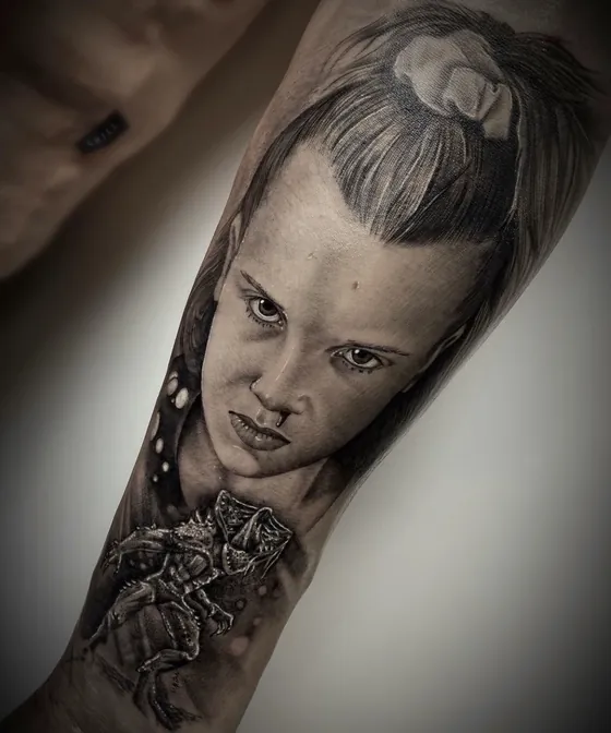 Porträt eines Mädchens mit strengem Blick und kleiner Kreatur darunter als Armtattoo
