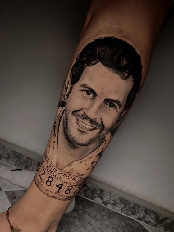 Realistisches Porträt eines lächelnden Mannes mit Nummerntafel als Unterarmtattoo